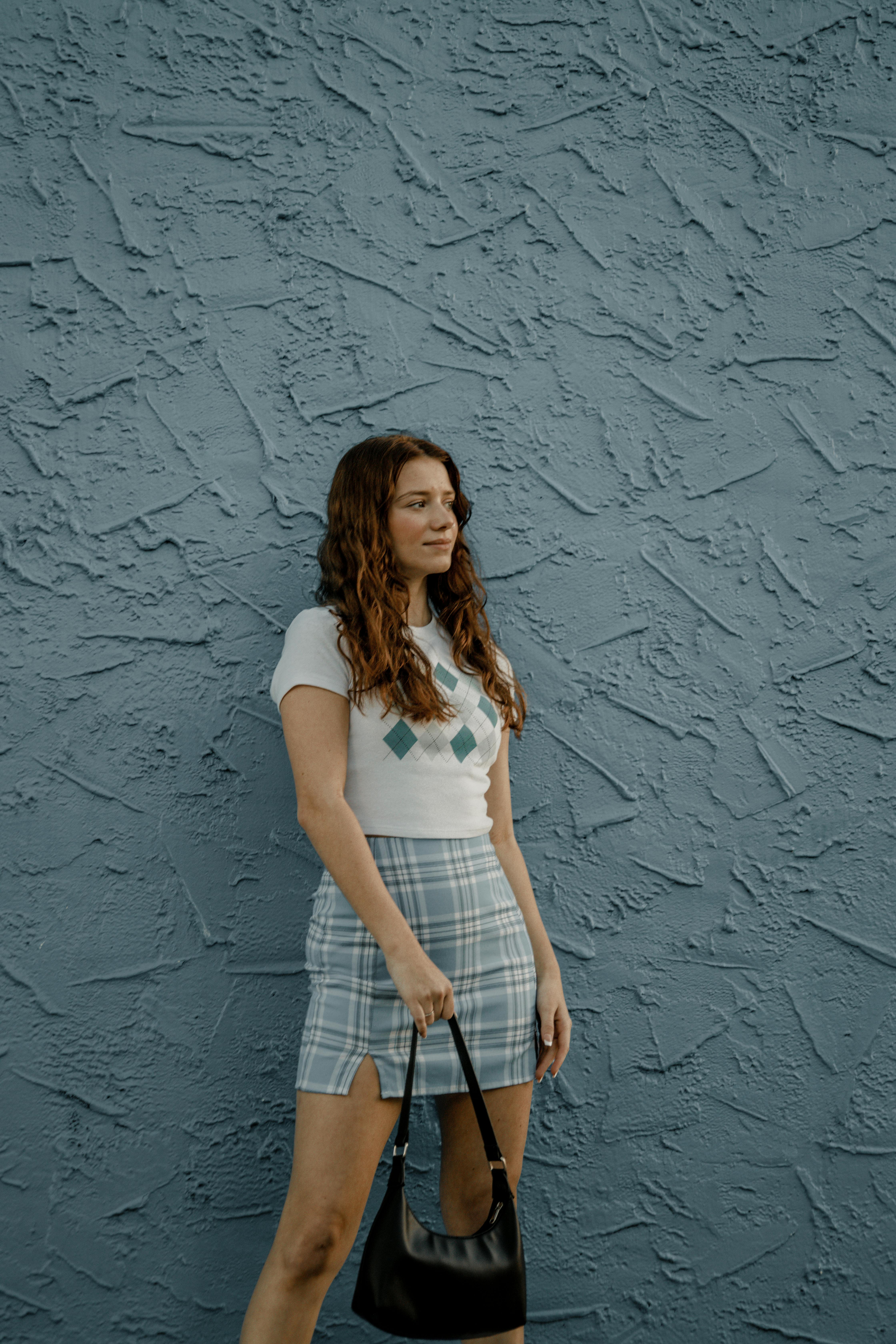 a woman in a plaid skirt and white t shirt