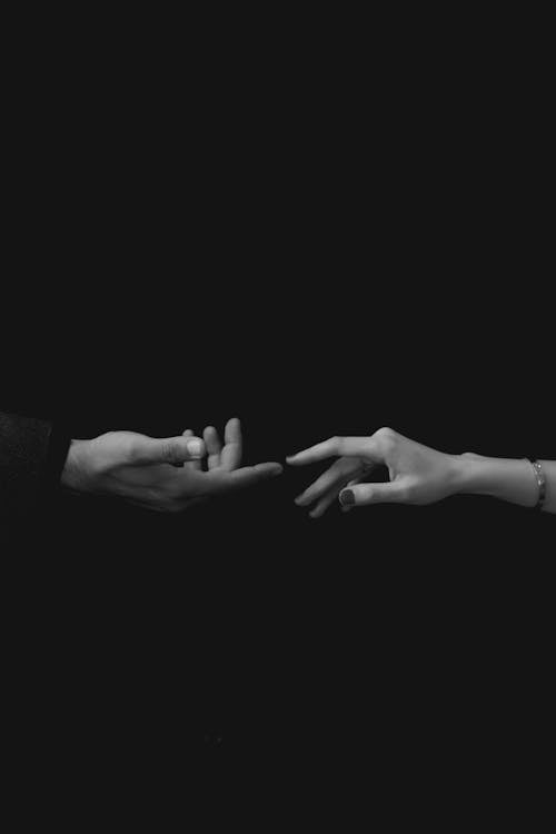 Close-up of Man and Woman Touching Hands on Black Background 