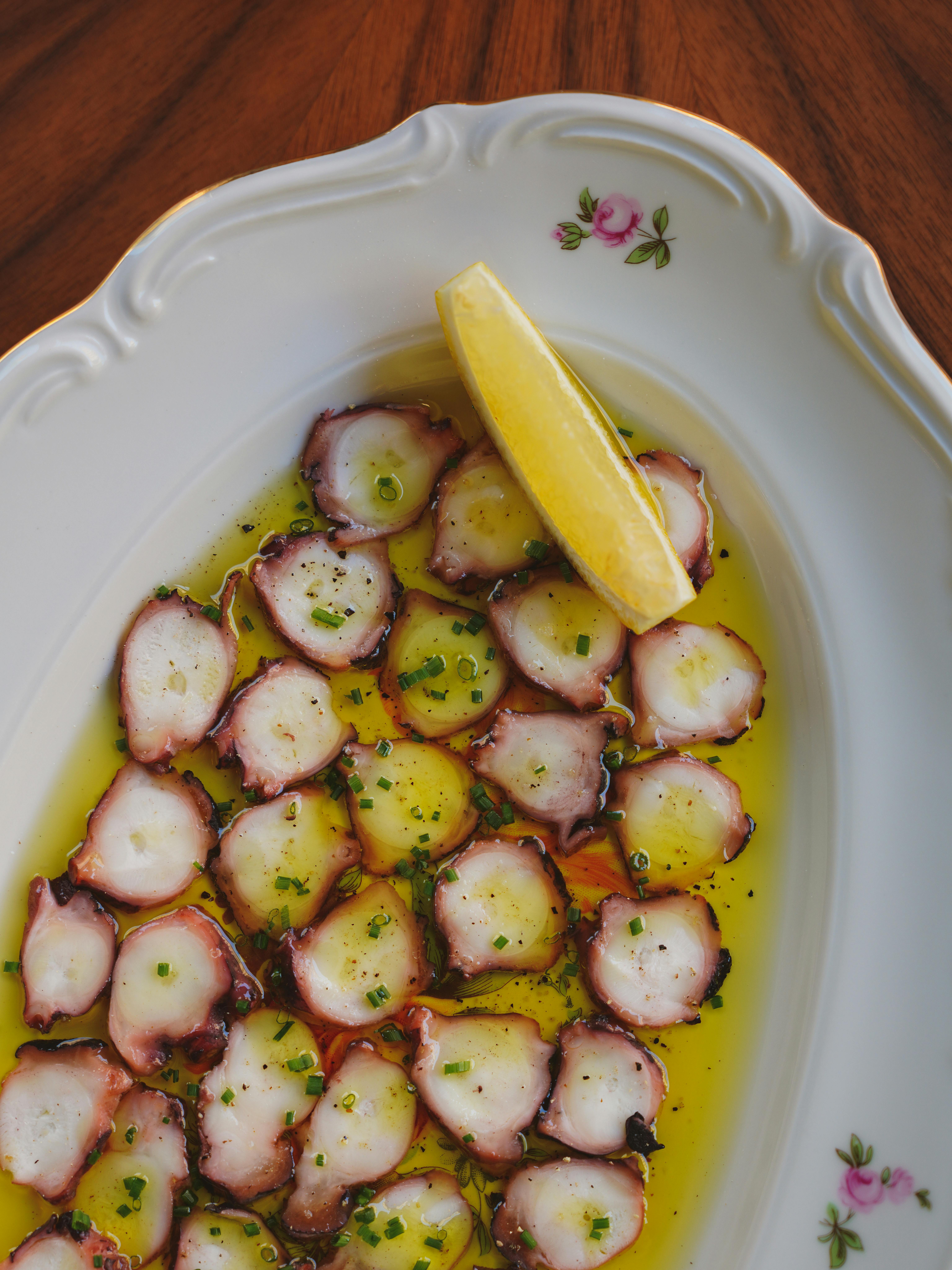 Delicious octopus carpaccio served with olive oil and lemon on a vintage plate.