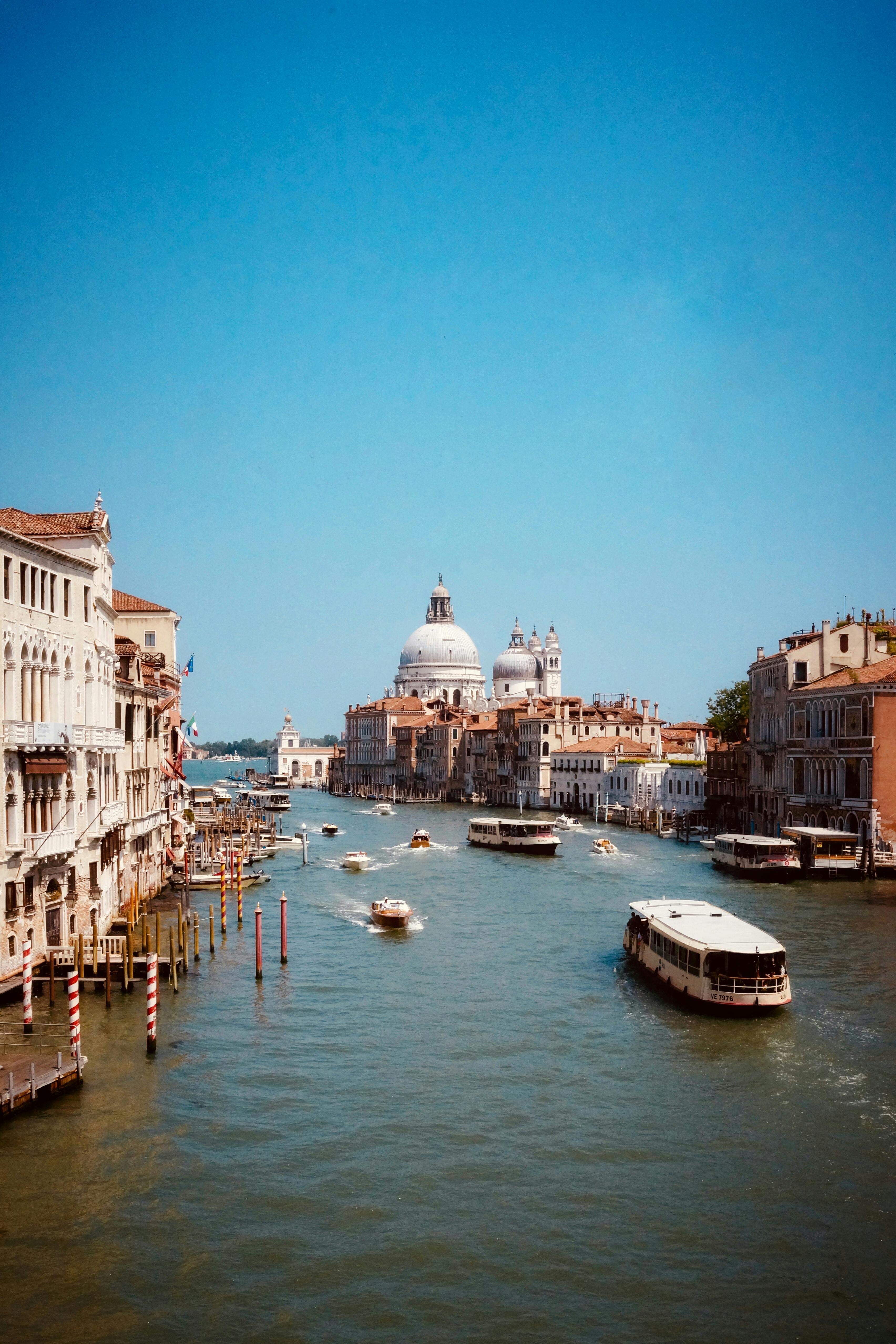 Aerial view of Venice's Grand Canal with boats and historic architecture under a clear sky.