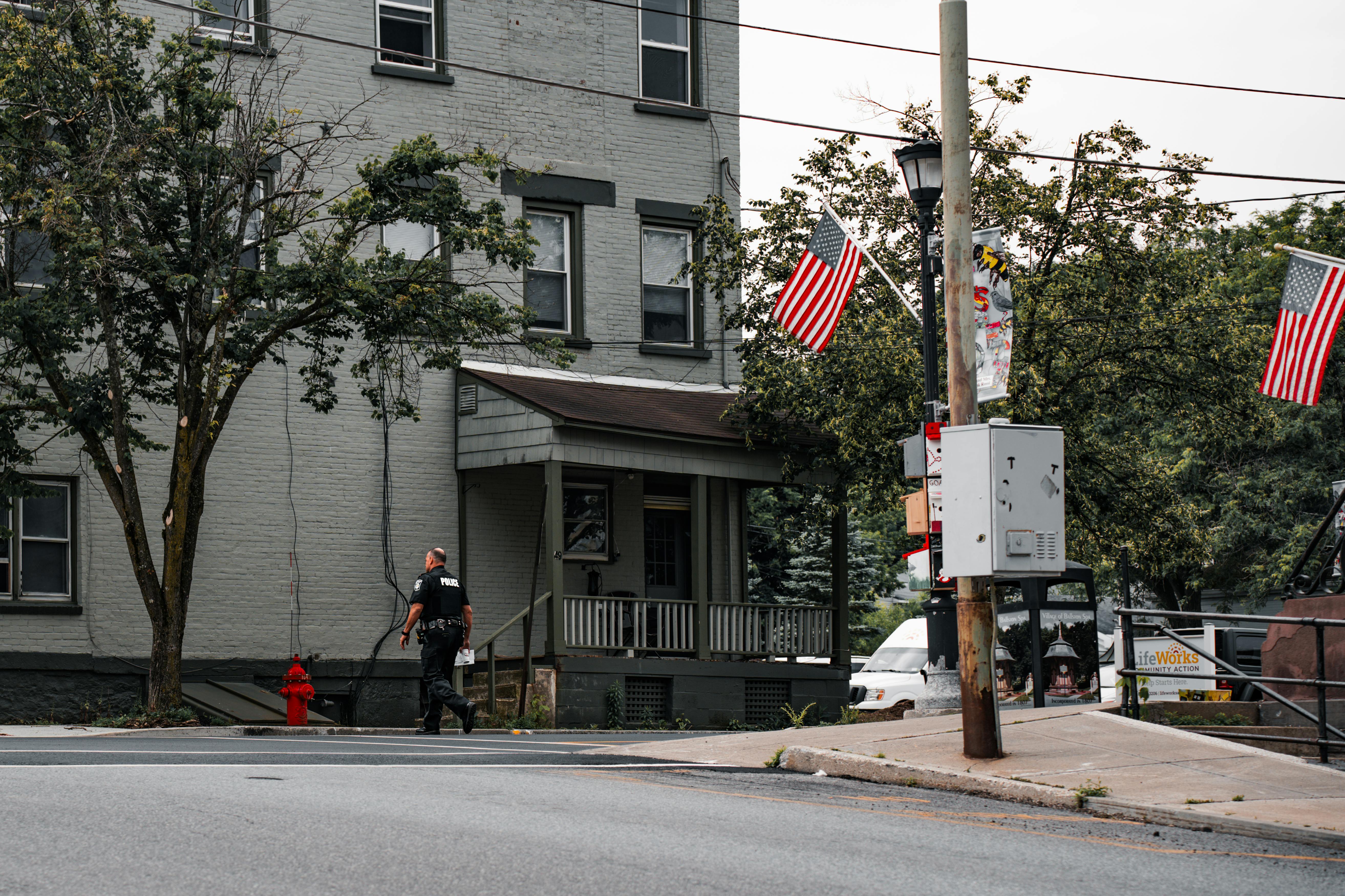 A Police Officer Crossing the Street in a Town Decorated with American Flags