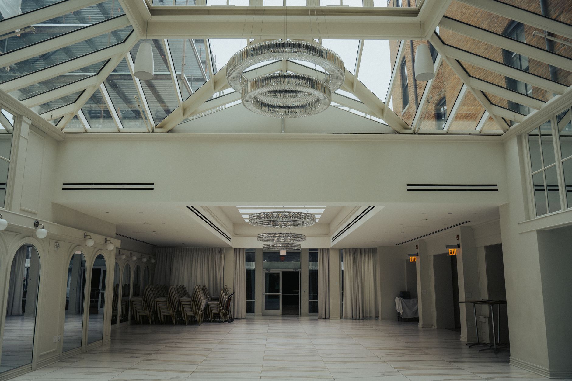 Spacious modern interior with glass ceiling and elegant chandeliers, perfect for events or weddings.