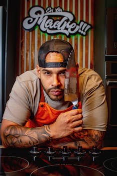Focused young chef posing with a knife in a modern kitchen setting.