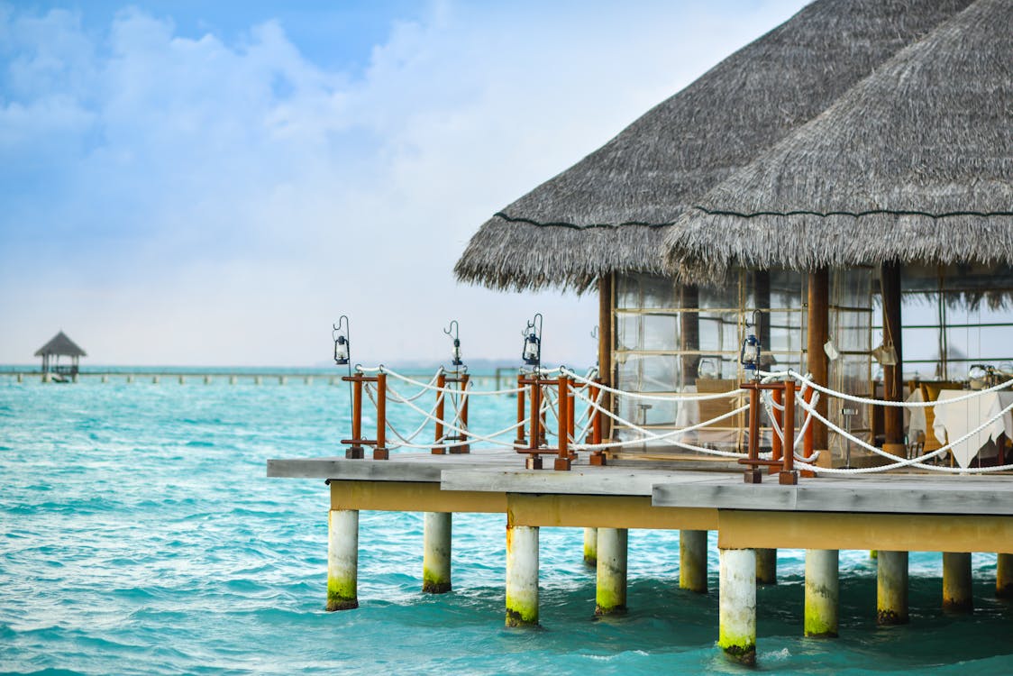 Brown Huts on Green Sea Under Blue Sky