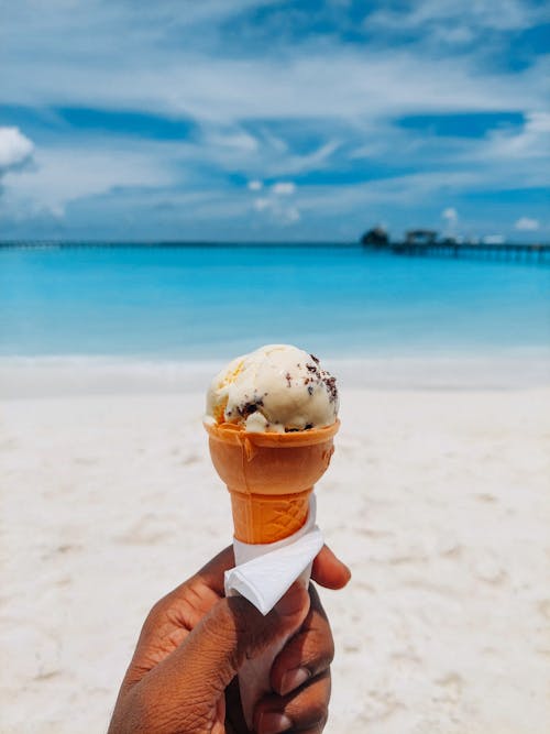 Hand Holding Ice Cream over Beach