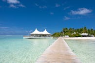 风景优美的热带度假村里，清澈蔚蓝的水面上架着一条木制木板路