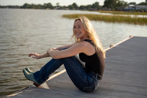 Young Woman Sitting on a Pier and Smiling 