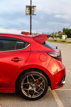 A stunning red sports hatchback car parked in an urban setting, showcasing sleek design and style.