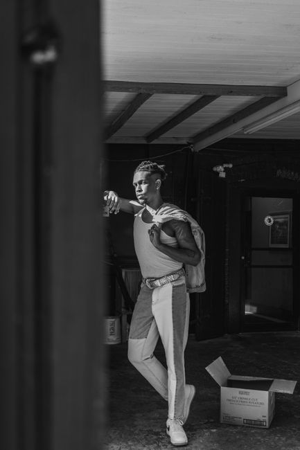Black and white portrait of a stylish young man in an urban indoor setting with natural light.