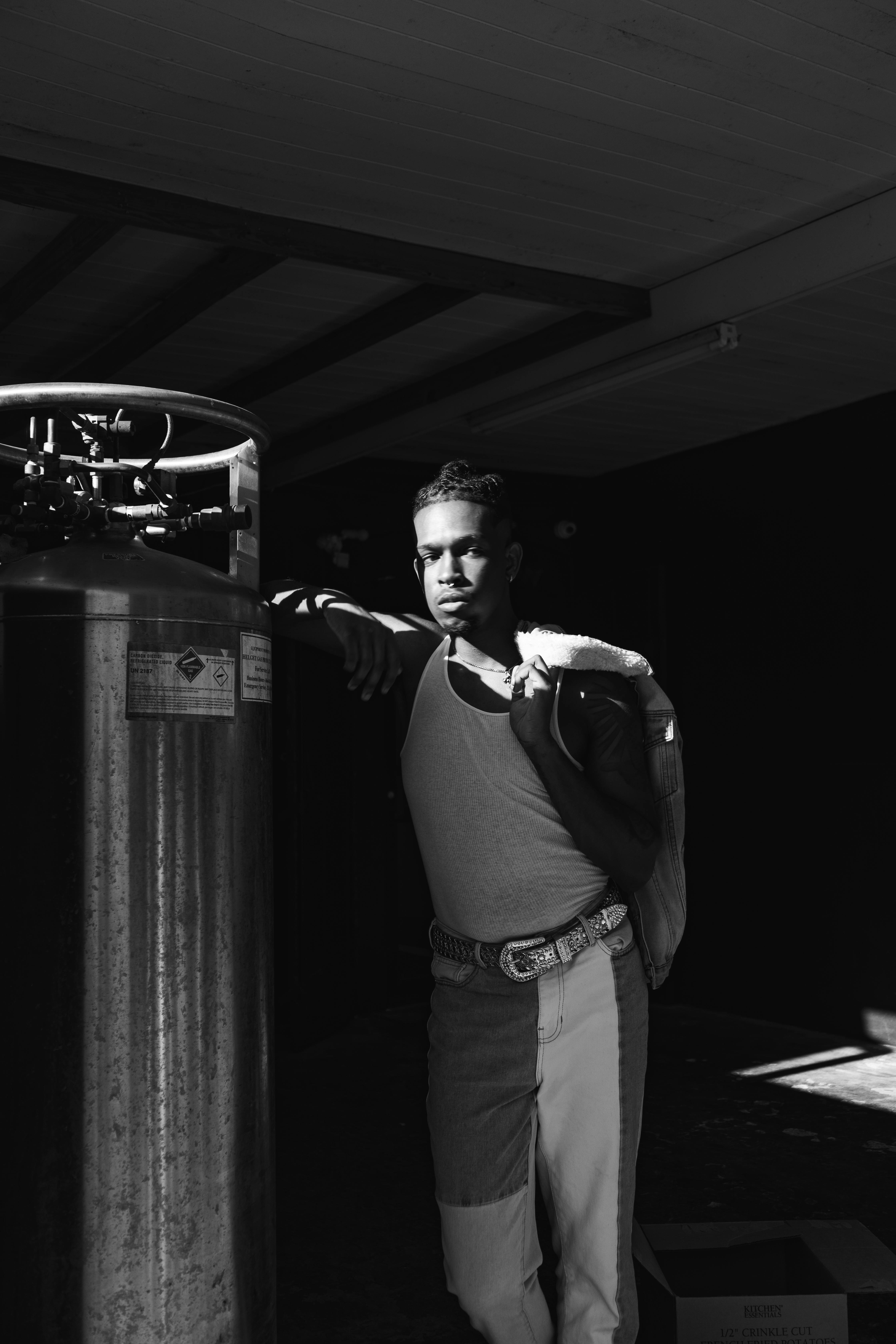 Moody black and white portrait of a man posing indoors with dramatic lighting.