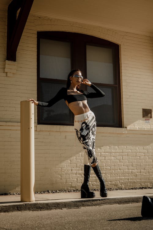 A woman in a crop top and leggings poses on a pole
