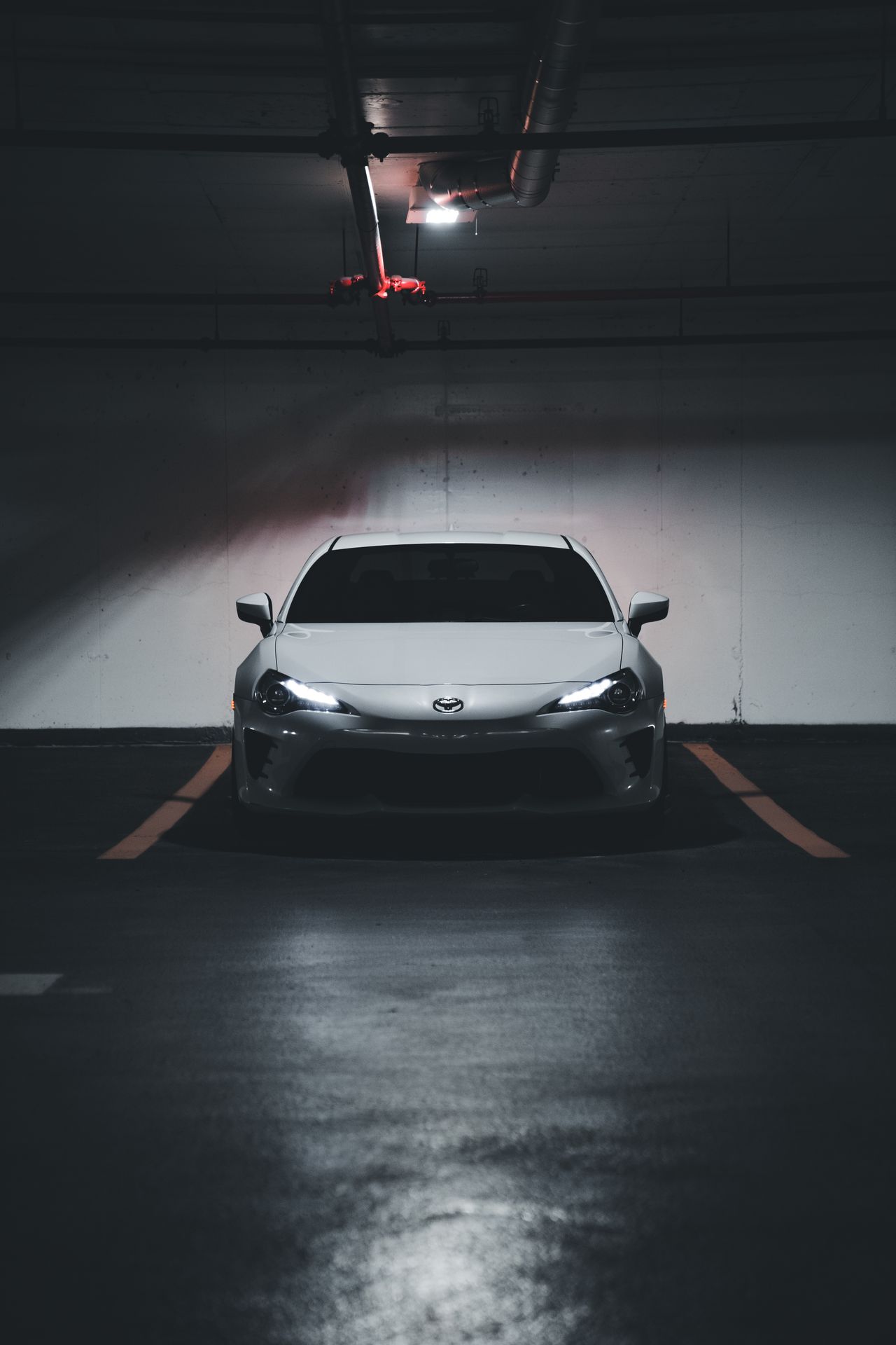 garage-gallery-sports-car-glossy-floor White sports car in a dark garage with a glossy reflective floor