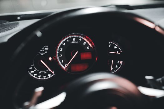 Detailed view of a modern car's dashboard with illuminated speedometer and gauges.