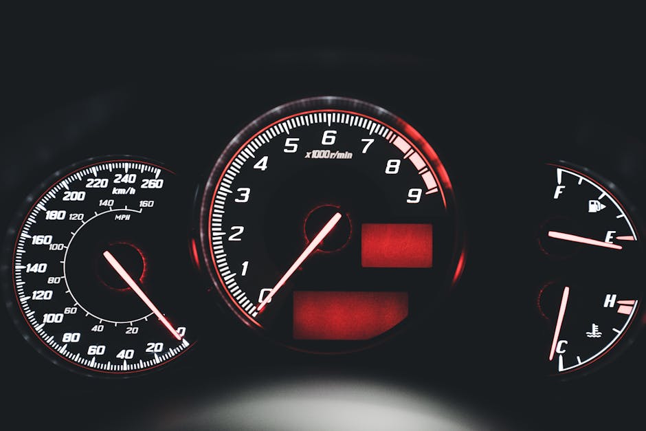 Close-up of an illuminated modern car dashboard with speedometer and gauges.