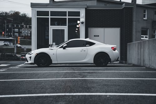 Free Side view of a sleek white sports car parked in a contemporary urban setting. Stock Photo