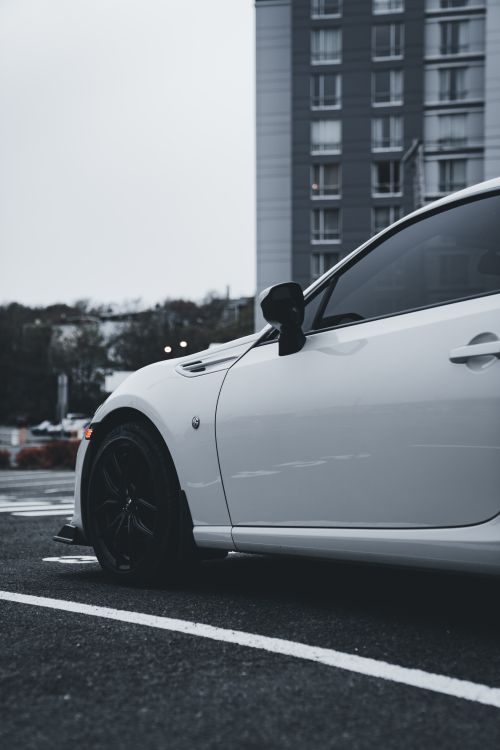 Free A modern white sports car parked outdoors in an urban setting, showcasing contemporary design. Stock Photo