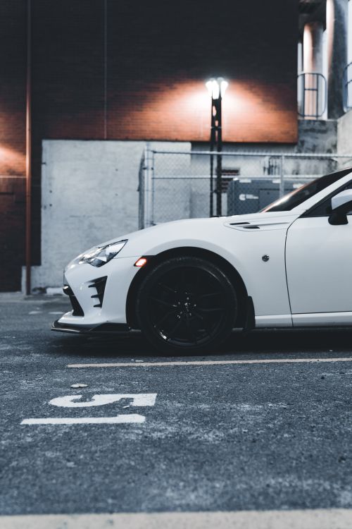 Free A sleek white sports car parked in an urban environment at night with modern lighting. Stock Photo