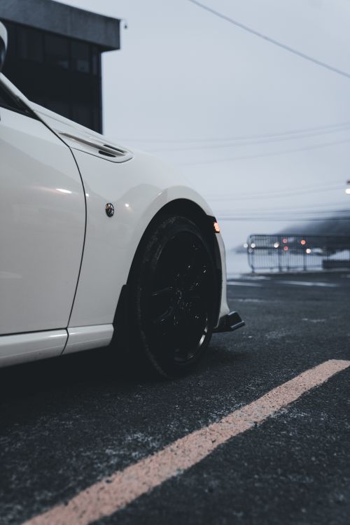 Free Close-up of a white sports car in an urban parking lot at dusk, exuding a modern vibe. Stock Photo
