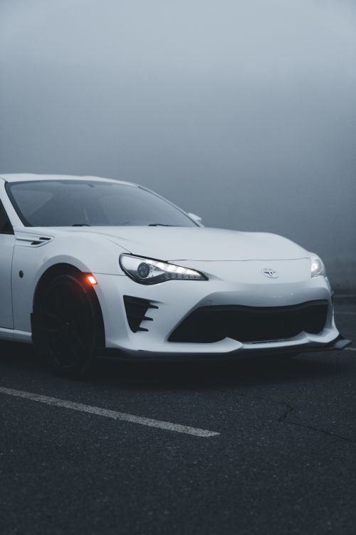 Free A modern white sports car photographed in a foggy parking lot, showcasing its sleek design. Stock Photo