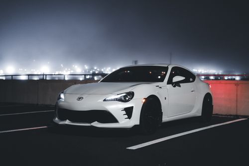 Free A modern white sports car parked in an urban setting at night, showcasing sleek design and contemporary style. Stock Photo