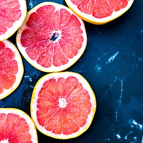 Free Vibrant grapefruit slices arranged on a dark marble surface, showcasing freshness and citrus appeal. Stock Photo