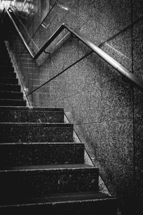 Free A low-angle shot of a modern concrete staircase with a metal handrail in an urban setting. Stock Photo