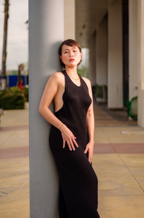 Pretty Woman in Black Summer Dress Leaning against a Pole