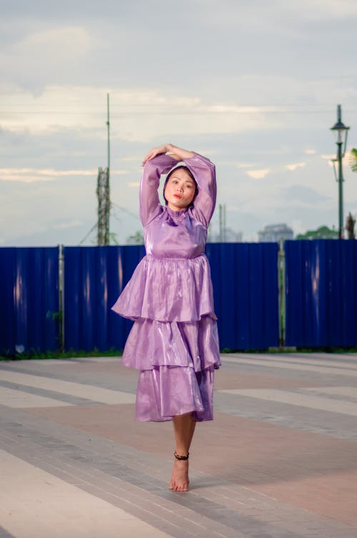 Woman in Purple Dress Posing with Arms Raised