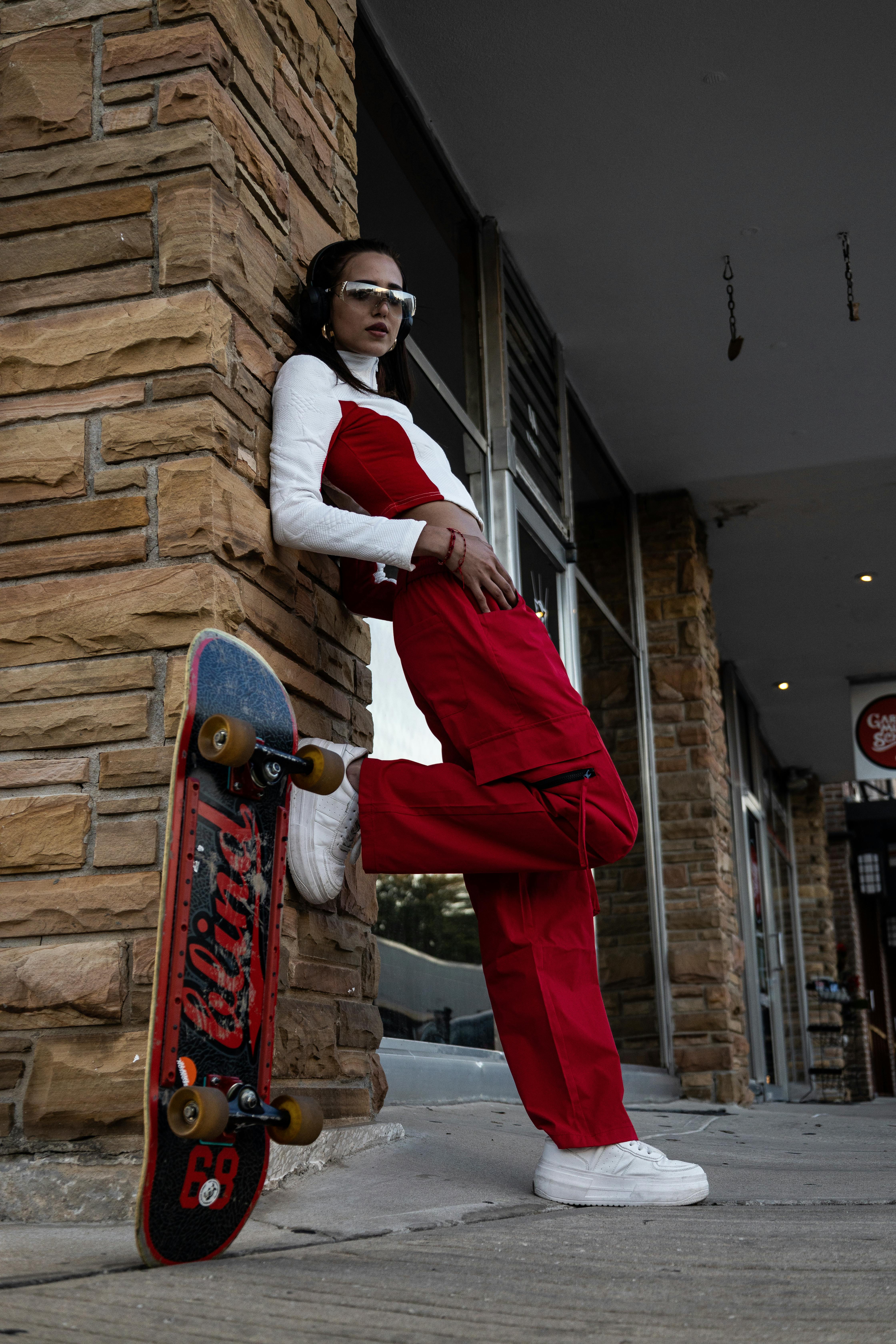 a woman leaning against a wall with her skateboard