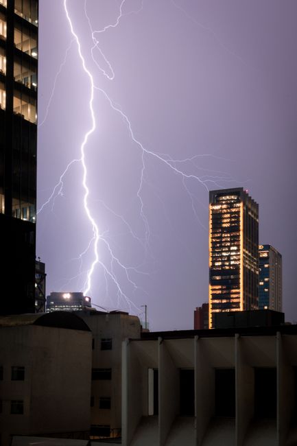 A striking lightning bolt illuminates the urban skyline of Mexico City, showcasing a dramatic evening storm.