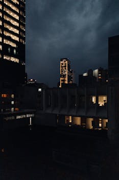 Stunning night view of CDMX skyline with lit skyscrapers against a cloudy sky.
