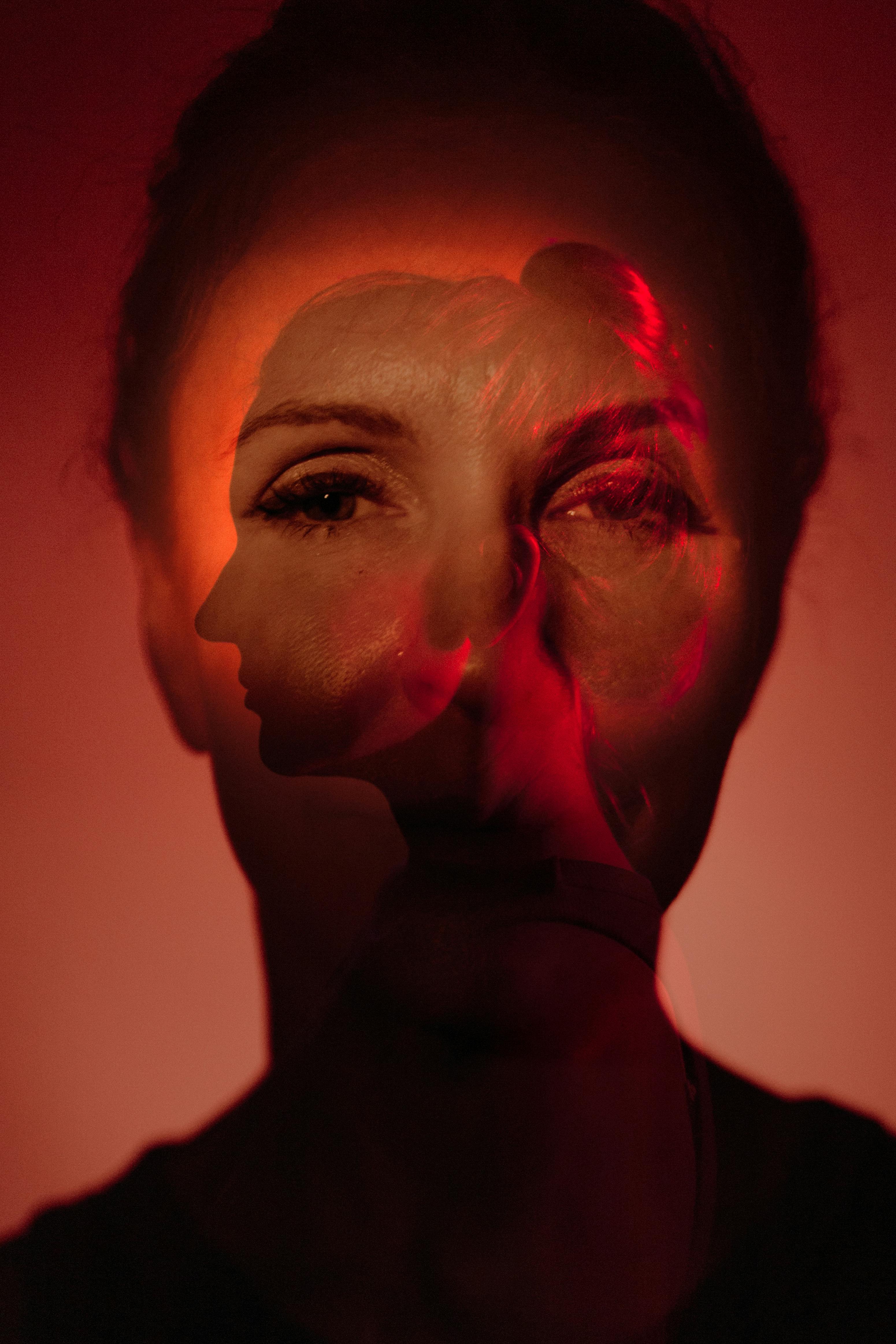 Creative double exposure of a woman's face with red lighting, creating an artistic effect.