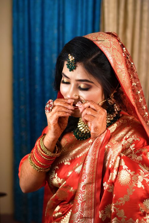 Free A woman in red traditional clothing adorned with jewelry, posing indoors. Stock Photo
