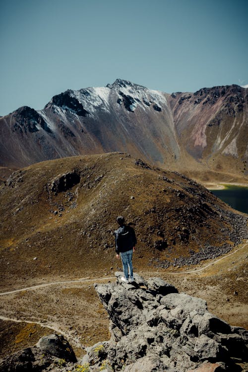 Tourist Standing on a Rock and Admiring the View of the Mountains