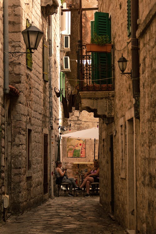 People Sitting in Narrow Alley in Town