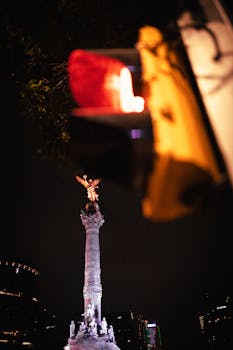 Capture of the Angel of Independence monument illuminated at night in Mexico City with blurred traffic light in the foreground.