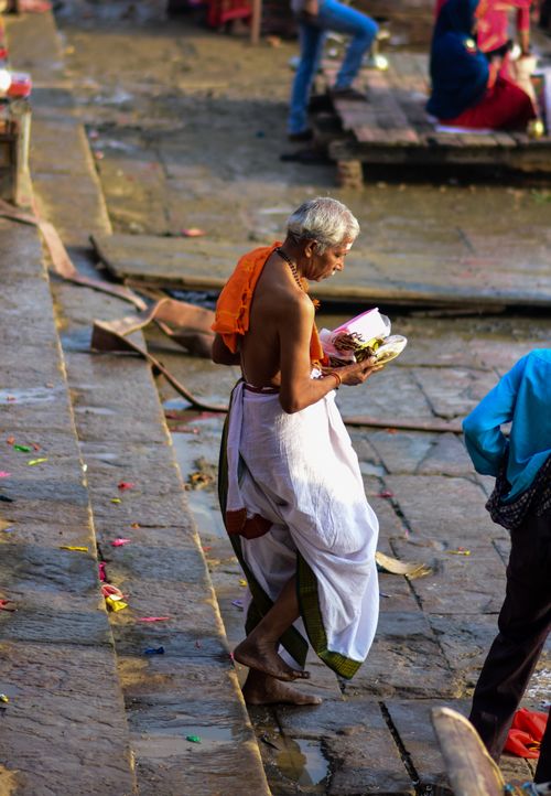 Free A senior Hindu ascetic carrying offerings on stone steps in Varanasi, India. Stock Photo