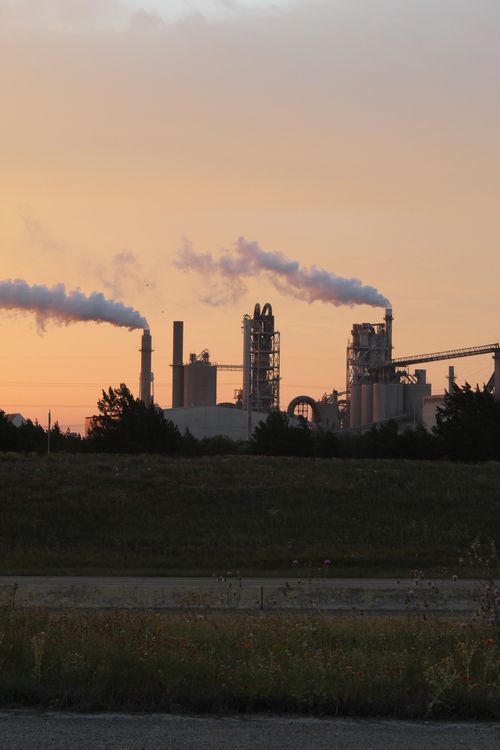 Free Factory chimneys releasing smoke during a vibrant sunset, highlighting industrial pollution. Stock Photo
