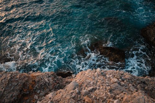 Free High angle view of waves crashing against a rocky coastline, showcasing natural erosion and beauty. Stock Photo