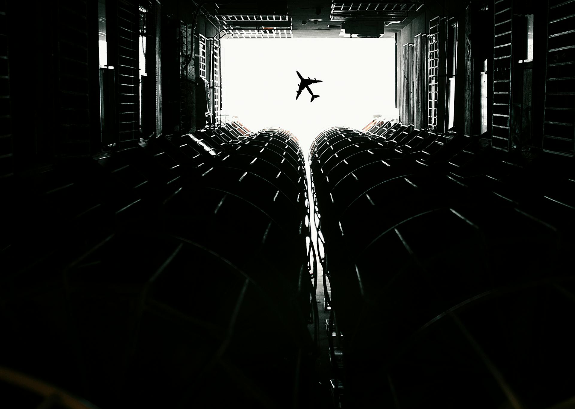 Dynamic contrast of airplane silhouette seen from a cargo container interior, highlighting modern transport.