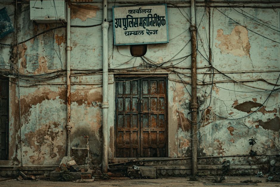 A decaying facade of an abandoned building with a weathered door and peeling paint, indicative of urban neglect.