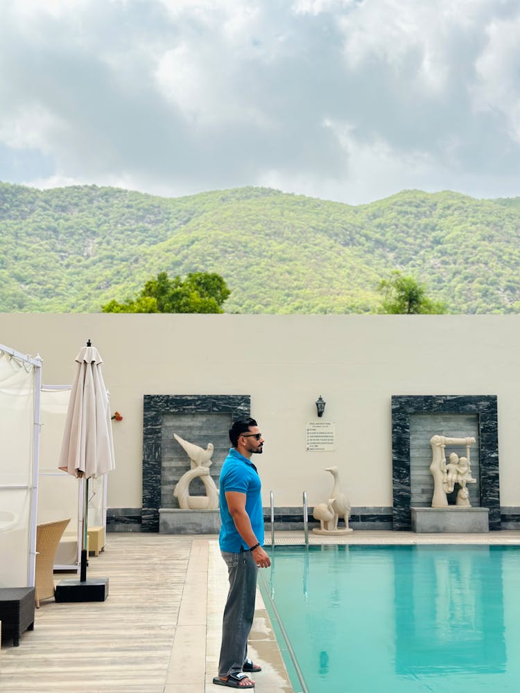 Man Standing On The Edge Of A Swimming Pool In A Luxury Estate