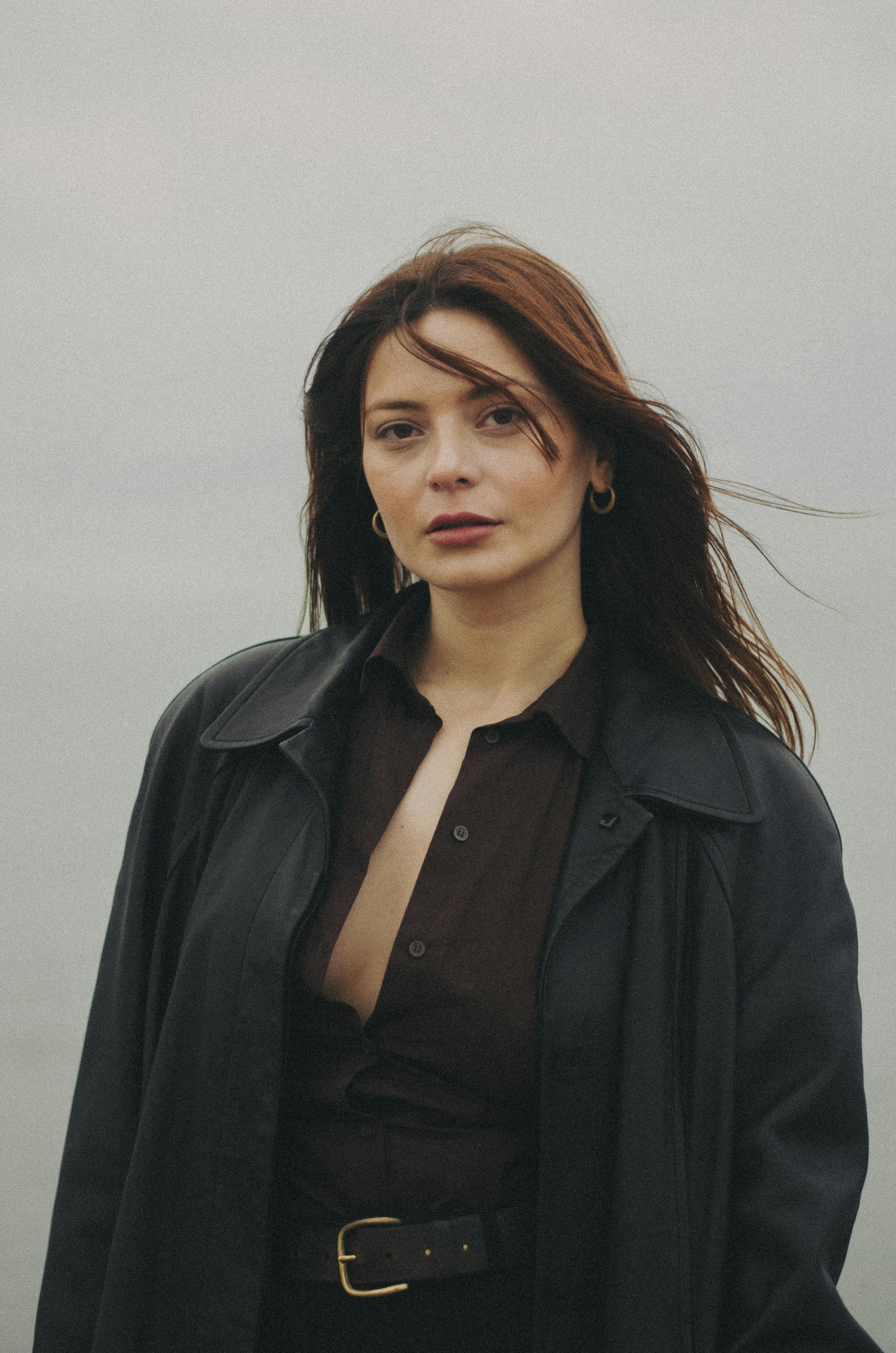 Elegant portrait of a woman standing outdoors in Baku, Azerbaijan, wearing a stylish coat.