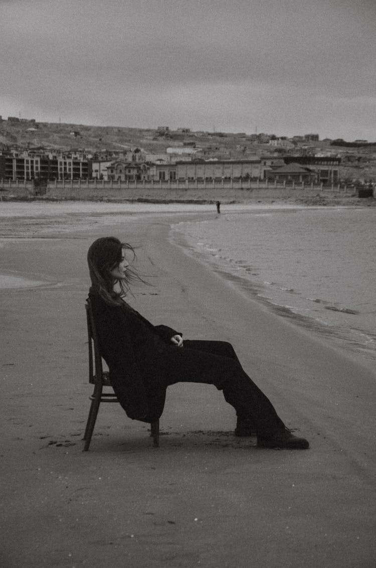 Black And White Picture Of A Woman Sitting On A Chair On The Beach 