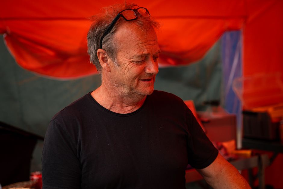 A senior adult with gray hair and glasses smiling under a vibrant red canopy, creating a warm atmosphere.