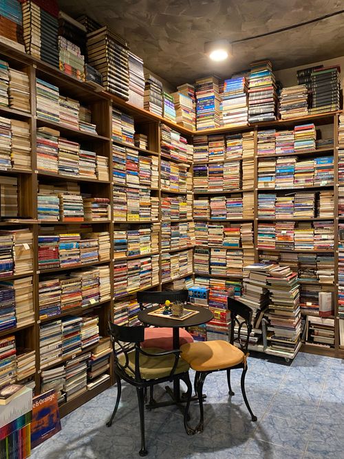 Free An inviting corner in a bookstore with floor-to-ceiling shelves packed with books and a small reading table. Stock Photo