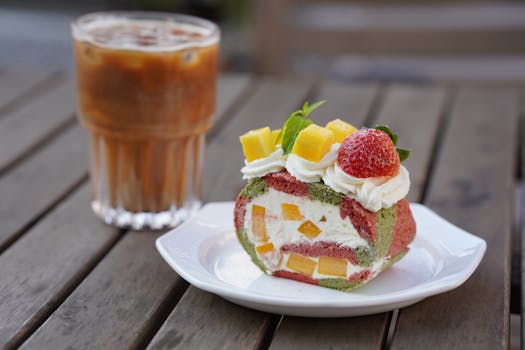 Delicious fruit-filled Swiss roll with iced coffee on a wooden table.