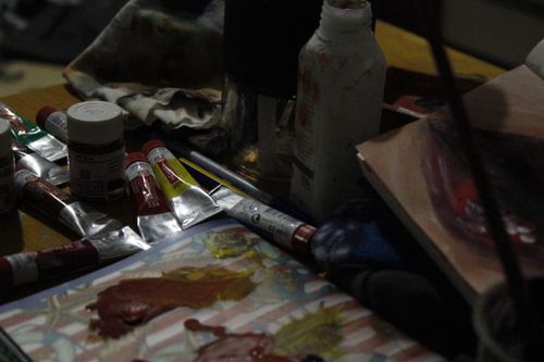 Free Close-up of art supplies including paint tubes and brushes on a cluttered desk showcasing creativity. Stock Photo