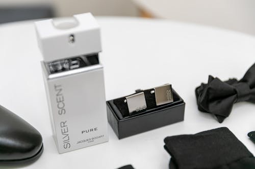 A Bottle of Perfume, a Bow Tie and Other Elegant Accessories on the Table 