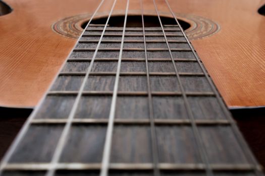 Detailed close-up of a classical guitar showing strings and fretboard in selective focus.